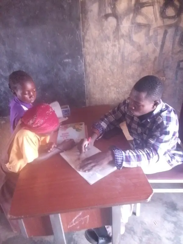 A teacher helping a student read in Northern Ghana